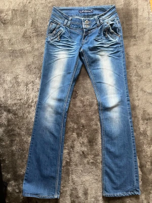 Blå bootcut jeans med lågmidja - Blåa bootcut jeans med låg midja och nit detaljer! Midjemått-34 cm innerbenslöngd- 83cm