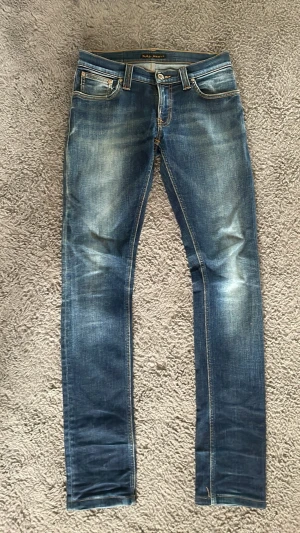 Blå slim fit jeans från Nudie Jeans - Snygga blå slim fit jeans från Nudie Jeans med snygg tvätt. Jeansen är i mycket bra skick, inga konstigheter. Storlek w26 l34, skulle inte säga att de är l34. Hör av dig direkt vid frågor eller funderingar!😁