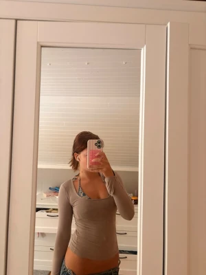 Beige långärmad tight topp - Snygg beige långärmad topp med tight passform och rundad halsringning. Tunt och stretchigt material som sitter figurnära och passar perfekt till jeans eller kjol. Enkel och stilren design som är lätt att matcha.
