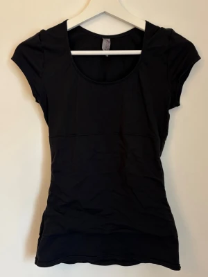 Svart tight kortärmad topp - Snygg svart topp med tight passform och rund halsringning. Kortärmad modell som passar perfekt till jeans eller kjol. Tillverkad i mjukt material som känns skönt mot huden. Köpt secondhand!