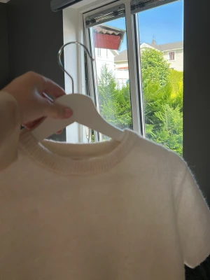 Vit fluffig kortärmad topp - Säljer en enkel och stilren vit topp med korta ärmar. Toppen har en mjuk, fluffig känsla och rund halsringning. Perfekt att matcha med jeans eller kjol för en clean look.