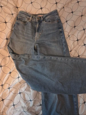 Ljusblå jeans från ONLY - Säljer ett par ljusblå mom jeans från ONLY i storlek XS. Jeansen har hög midja, raka ben och klassisk femficksdesign. Tillverkade i mjuk denim med knapp- och dragkedjegylf. Perfekta för en avslappnad och trendig look.