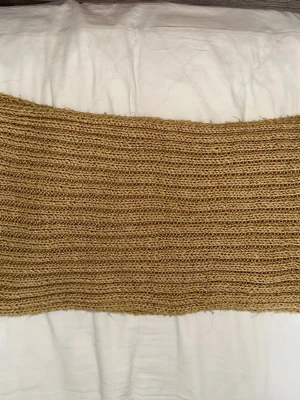 Beige stickad tubhalsduk - Säljer en chunky stickad tubhalsduk i beige. Halsduken har ett grovt ribbat mönster och är riktigt mjuk och skön. Perfekt för att hålla värmen under kyliga dagar och enkel att styla till olika outfits.