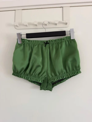 Gröna satinshorts från Zara X Disney - Snygga gröna shorts i satin från Zara Disney-kollektionen. De har en loose passform, elastisk midja och en liten svart rosett framtill. Perfekta för sommarens alla dagar och ger en skön, avslappnad vibe. Aldrig använda