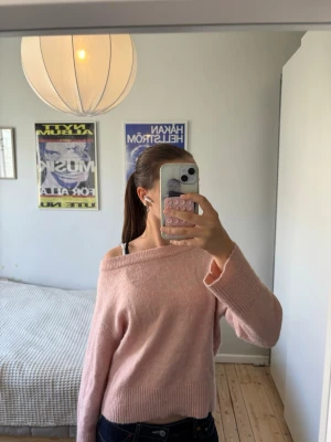 Ljusrosa stickad off shoulder-tröja - Ljusrosa stickad tröja med off shoulder-design och långa ärmar. Tröjan har bred ribbstickad mudd vid ärmslut och nederkant. Man kan välja att ha den off shoulder eller bara vanligt eftersom att halsen är så bred!🩷