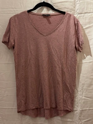 Ljusrosa v-ringad t-shirt - En enkel och snygg ljusrosa t-shirt med v-ringning och korta ärmar. Tillverkad i mjuk bomull som känns skön mot huden. Passar perfekt till jeans eller shorts för en avslappnad look.