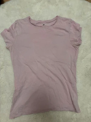 Basic t-shirt - En enkel och stilren ljusrosa t-shirt med rund hals och korta ärmar. Perfekt att matcha med jeans eller kjol för en avslappnad look. Tillverkad i mjuk bomull som känns skön mot huden.