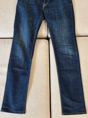 Mörkblå tramarossa jeans - Snygga mörkblå jeans från Tramarossa med raka ben och tydliga kontrastsömmar. Klassisk femficksmodell och knappgylf. Jeansen har en tvättad look och detaljer i vitt och rött på insidan. Perfekta för en avslappnad men stilren outfit.