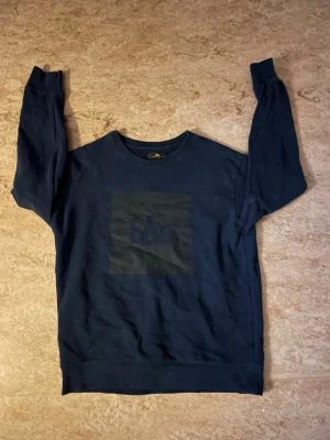 Lee tröja - En enkel och stilren mörkblå sweatshirt från lee med rund hals och ett diskret tryck på bröstet. Tröjan har långa ärmar och ribbade muddar vid ärmslut och nederkant. Perfekt för en avslappnad look. Storlek: M . Bara skriva om du vill ha mått!📏😊