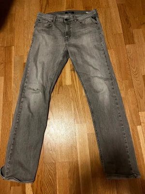 Replay grå jeans straight fit - Snygga grå jeans från Replay med klassisk femficksdesign och raka ben. Jeansen har en diskret tvättad look och svarta detaljer vid knapparna. Passar dig som gillar stilrena och tidlösa jeans med bekväm passform. Jeansen passar alla runt 175 långa skor och har inga deffekter förutom att lappen där bak är sönder. Pris kan diskuteras 🙌