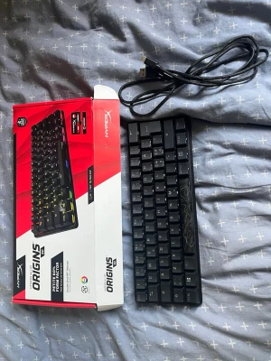 HyperX Origins Core mekaniskt tangentbord - Säljer ett HyperX Origins Core mekaniskt tangentbord i svart med RGB-belysning. Kompakt design utan numerisk del, USB-kabel medföljer. Tangentbordet har en snygg och stilren look med diskreta mönster på vissa tangenter.