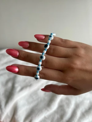 Onda ögat armband - Snyggt armband med vita onda ögat pärlor. Armbandet har en tunn silverfärgad kedja och justerbart spänne så det passar de flesta handleder. Perfekt accessoar för dig som gillar trendiga detaljer och vill sticka ut lite extra.