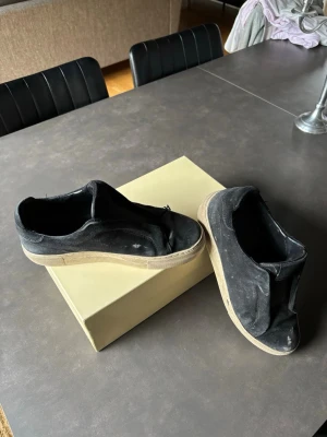 Svarta sneakers från Axel Arigato - Svarta låga sneakers från Axel Arigato med canvasöverdel och vit sula. Klassisk och stilren design utan synliga loggor på skon. Perfekta för en clean och avslappnad look.