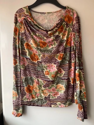 Blommig långärmad topp med draperad hals - Unik långärmad topp med blommigt mönster i orange, rosa och grönt. Sitter fint. Etikett saknas , passar till stl M-L
