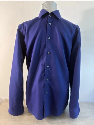 Blå långärmad skjorta Eton - 💙 Elegant Eton-skjorta med fin struktur i tyget 👔 Slim Fit 📏 Storlek 39 / 15½ – M 🌿 100% bomull ✨ Svenskt premiumvarumärke ⚠️ Lätt missfärgning på kragen, se bild 📐 Mått finns på bilderna