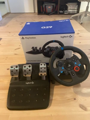 Logitech G29 ratt och pedaler - Säljer en Logitech G29 ratt och pedalset. Ratten har svart läderklädsel, blå detaljer och flera knappar för spelkontroll. Pedalerna är i metall och svart plast, perfekta för racing-upplevelser hemma. Kompatibel med PlayStation och PC. Ser ut och funkar som nytt! Pris kan diskuteras.