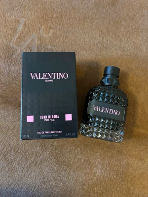 Valentino Uomo Born In Roma Intense 100ml - Valentino Uomo Born In Roma Intense är en parfym i en lyxig svart flaska med nitar och rosa detaljer. Flaskan rymmer 100 ml och har en unik, edgy design som sticker ut på hyllan. Doften är Eau de Parfum Intense och passar dig som vill ha något kraftfullt och modernt.