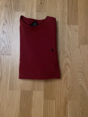 Mörkröd långärmad tröja från polo ralph lauren - En stilren mörkröd långärmad tröja från polo ralph lauren med rund halsringning och diskret broderad logga på bröstet. Tröjan har en rak passform och är tillverkad i ett mjukt material som passar perfekt till många olika outfits. storleken är L i barnstorlek, Aldrig använd 