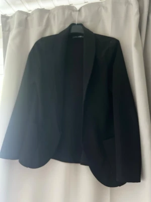 Svart klassisk kavaj - Snygg svart kavaj med enkel, rak passform och klassiska slag. Perfekt att styla över en topp eller skjorta. Kavajen har två fickor framtill och är tillverkad i ett mjukt tyg som ger en stilren look.