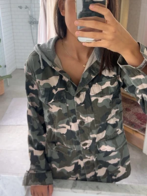 Niche Militär mönstrad jacka  - Säljer en grön  camouflage vindjacka med grå huva. Niche , tunn och sval , har aldrig använt , nytvättad , niche och annorlunda 