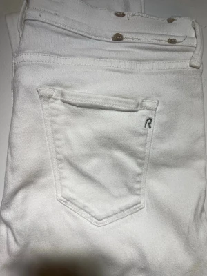 Vita slim jeans med fickdetalj - Snygga vita jeans i slim fit-modell med klassisk femficksdesign och en liten broderad detalj på bakfickan. Jeansen har knappgylf och är tillverkade i ett mjukt bomullsmaterial med stretch för extra komfort. W31, L32. Väldigt slim kan vara att det är till dam. 