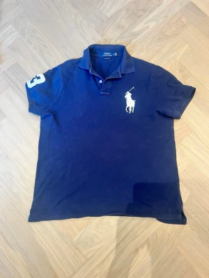 Marinblå pikétröja från Polo Ralph Lauren - Klassisk marinblå pikétröja från Polo Ralph Lauren med big pony logga på bröstet. Bara o skriva kring funderingar 