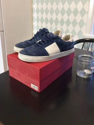 Valentino flycrews Navy blue  - Snygga sneakers i blå mocka med vita detaljer. I storlek 41 men passar 42 perfa. En defekt på ena skon därför säljes för billigare än alla andra. 3 nitar saknas på ena skon men du får med 4 nitar vid köpet. Fraktas samma på samma dag. Hör av er om ni har frågor eller funderingar, (priset är inte hugget i sten)