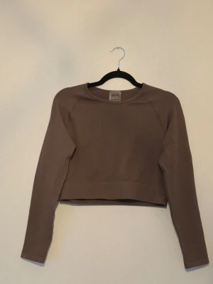 Aim’n ribbad cropped träningstopp Macchiato XXL - 🤎 Ribbad cropped långärmad träningstopp från Aim’n i färgen Macchiato. Snygg figurnära modell i mjukt och stretchigt material, perfekt till träning eller vardags.  🔖 Storlek: XXL  📏 Mått liggande: • Bredd nedtill: ca 39 cm • Längd: ca 42 cm • Innerärm: ca 48 cm  💡 Upplevs något liten i storleken – jämför gärna måtten med ett plagg som passar.  🧵 92 % polyamid, 8 % elastan  ✨ Superfint skick, knappt använd. Inga anmärkningar upptäckta.  🏷️ Nypris: 549 kr.