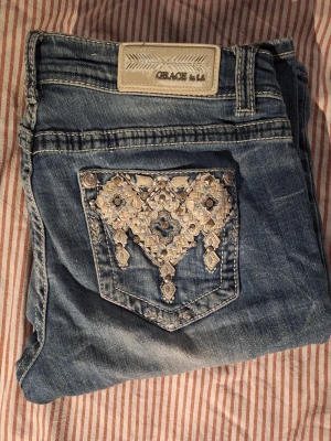 Bootcut jeans low waist - Blåa bootcut jeans från Grace in LA. Köpta på mall of scandinivia för 1100 kr. Supersnygga fickor och detaljer men passar tyvärr inte så bra på mig längre. Ca 80cm midja. Innerbenslängd ca 82cm. ❣️❣️Kontakta mig för fler mått/bilder✨️