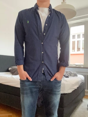 Mörkblå Ralph lauren skjorta - Säljer en skitsnygg raffe skjorta i utmärkt skick. Knappast använd och passar till vilken outfit du vill.                                                                                    Kom pm för frågor!!