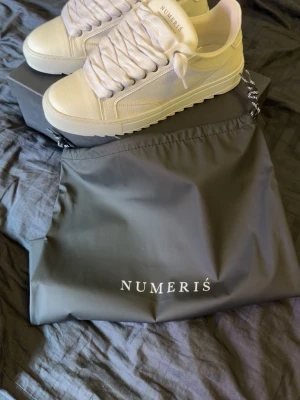 Vita sneakers från Numeris - Säljer ett par stilrena vita sneakers från Numeris. Skorna har chunky sula, breda vita skosnören och är tillverkade i slätt läder. Klassisk low-top design med diskret branding på plösen. Perfekta för dig som gillar minimalistisk och clean stil. Nypris ligger på 2500. Helt oanvända med box och skopåse.
