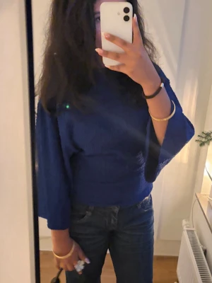 Blå topp med vida ärmar - Säljer en snygg blå topp med trekvartsärm och lös passform. Toppen har en enkel design utan mönster och är perfekt att styla med jeans eller kjol. Materialet känns mjukt och bekvämt mot huden.