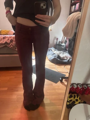 Vinröda bootcut jeans - Säljer ett par vinröda bootcut jeans med klassisk femficksmodell och knappgylf. Jeansen har en snygg utsvängd passform från knät och ner. 39 cm tvärs över midjan, 86 cm innerbenslängd. Köpta på Vinted.