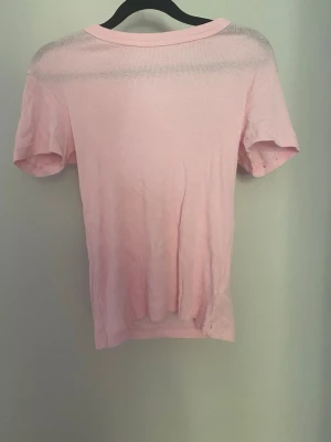 Ljusrosa kortärmad t-shirt - Säljer en ljusrosa t-shirt i mjukt bomullsmaterial. T-shirten har klassisk rund halsringning och korta ärmar. Enkel och stilren design som passar till det mesta. Perfekt basplagg för garderoben.