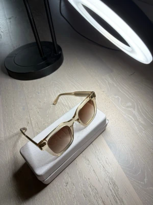 Chimi  solglasögon - Snygga väldigt trendiga solglasög med transparent beige båge och fyrkantig form från märket Chimi! . Dom Kommer med ett stilrent vitt fodral som skyddar glasögonen när du inte använder dem. Ny pris brukar ligga runt 1400kr