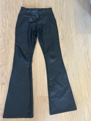 Svarta utsvängda byxor i fuskskinn Zara  stl 164/xs - Säljer ett par svarta byxor i fuskskinn med utsvängda ben. Byxorna har 2 fejkfickor fram. Som nya! 