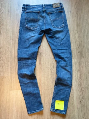 Nudie Jeans 👖  - Nudie Jeans – Strl W32/L34 👖 Ljusblå jeans från Nudie Jeans i klassisk modell. Snygg tvätt med ikoniska bakfickor och en passform som passar till det mesta. I fint begagnat skick.  📏 Storlek: W32/L34 📦 Skick: Bra begagnat skick 💬 Hör gärna av dig vid frågor eller om du vill ha fler bilder!