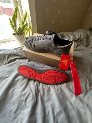 Louboutin skor med spikar färg grå - Gråa Christian Louboutin med spikar, ikonisk röd sula och storlek 44. En sko som inte direkt ber om uppmärksamhet – den tar den. 🩶🔻  Storlek: 44 Färg: Grå Detaljer: Spikar + röd signatursula Style: Lyxig, edgy & statement  Ett par skor för den som hellre lämnar ett avtryck än följer strömmen. 🔥 Dem är testade en gång inomhus annars aldrig använda❤️