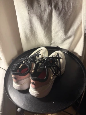 Adizero select 3.0 Adidas basketskor - Säljer ett par snygga basketskor i vitt med svarta och rosa detaljer. Skorna har svart snörning och en sportig design med mesh-material på ovansidan. Perfekta för träning. Skorna har en tjock sula och låg profil. STORLEK 44,5-45