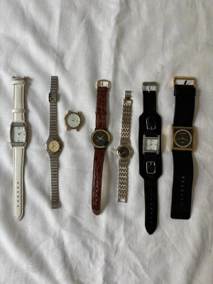 7 st klockor  - Säljer ett paket med sju olika vintage klockor i olika stilar. Här finns både klassiska och moderna former, med armband i vitt, svart, brunt skinn och metall. Flera urtavlor i silver, guld och svart. Perfekt för dig som vill ha unika accessoarer till din stil. Alla tickar om de får nya batterier, vilket de inte har (jag har inte tillräckligt med batterier hemma) . Säljes för 70 kr / st i befintligt skick. Pris kan diskuteras vid snabb försäljning. 