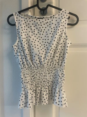 Vit prickig ärmlös topp med volang - Nu säljer jag min fina prickiga topp från Gina i storlek S😌 Använd några gånger men passar inte mig längre, ge prisförslag🩷 köpt för 30€