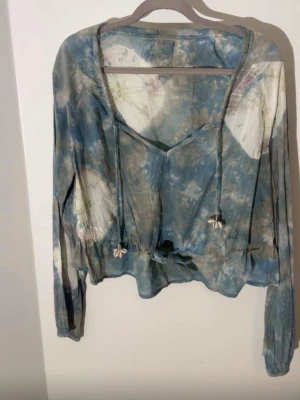 SixtyDays blå batikblus – boho style - Snygg och unik blus från SixtyDays i ett vackert blått/vitt batikmönster. Fina detaljer med knytband framtill, små blomdetaljer och en feminin, bohemisk känsla. Perfekt till jeans, kjol eller shorts – en riktig statement-topp som passar både vardag och semester 🌸 Är i väldigt fint skick men lite äldre tröja då de va min mammas , kollade deras hemsida priserna ligger på 1100kr ca .  Hittar inte storlek men uppskattar till storlek s/m