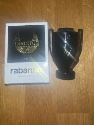 50ml Paco Rabanne Invictus Victory Parfym - 50ml kvar Parfymen Invictus Victory från Paco Rabanne kommer i en svart, troféformad flaska med guldiga detaljer. Förpackningen är vit med svart och guld, och har en lyxig känsla. Doften är intensiv och maskulin, perfekt för dig som gillar kraftfulla parfymer.