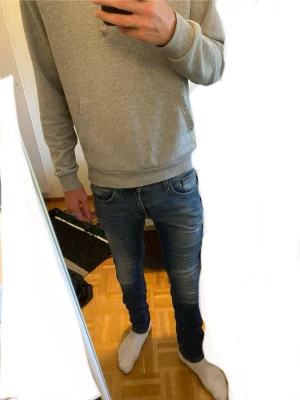 Blå slim fit Tommy Jeans - Snygga blå slim fit jeans med lätt slitning och stretchigt material. Klassisk femficksmodell med normal midja och smala ben. Perfekta för en avslappnad och trendig look. Modellen är about 180cm och 70kg. Model Tommy Jeans, Scanton. Size 28/32