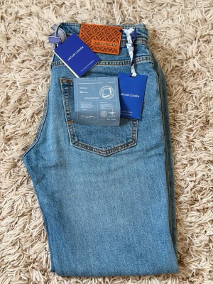 JACOB COHËN jeans, storlek 30, nästan oanvända - Säljer ett par exklusiva Jacob Cohën jeans i storlek 30. Jeans i klassisk ljusblå tvätt med en stilren och tidlös look.  Endast använda cirka 5 gånger och är därför i mycket fint skick. Inga tydliga skador eller större tecken på användning. Jeansens originaldetaljer och etiketter finns kvar, inklusive tags och dokumentation.  Detaljer: Storlek: 30 Färg: Ljusblå Märke: Jacob Cohën Skick: Mycket fint skick Använda: Cirka 5 gånger Tillverkade i Italien Originaltags och dokumentation ingår  