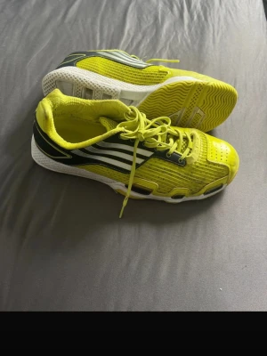 Gula sneakers med svarta detaljer - Snygga sneakers i gult med svarta och vita detaljer samt vita sulor. Skorna har en sportig design med meshpaneler för bra ventilation och klassisk snörning. Perfekta för dig som vill sticka ut med färg på fötterna.