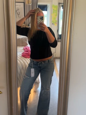 Ljusblå baggy jeans med slitningar - Säljer ett par ljusblå baggy jeans med slitningar på både lår och knä. Jeansen har låg midja, raka ben.  Helt oanvände och säljer enbart för de inte kommer till användning! 