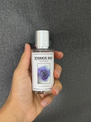 Zosimos 109.0 Eau de Parfum - Zosimos 109.0 Eau de Parfum i en stilren, genomskinlig glasflaska med silverfärgad kork. Etiketten har en modern design med lila och blå toner samt grafiskt motiv. Perfekt för dig som gillar unika och konstnärliga dofter.