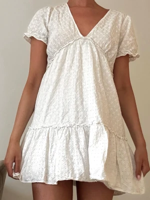 Söt vit broderad studentklänning med volang - Söt vit kortklänning i bomull med broderade detaljer och volang nedtill. Klänningen har v-ringning, puffiga korta ärmar och en luftig passform som ger en romantisk vibe. Perfekt för varma dagar och sommarens alla tillfällen. Jag har klippt av innerkjolen någon cm då den krympt ca 1-2cm i tvätten (se bild 4)🤍
