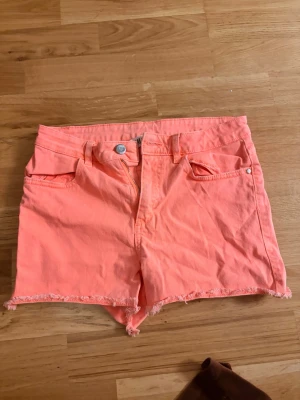 Coral/ korall shorts - Säljer ett par korall färgade shorts, perfekta nu till sommaren!! Står strl 164 vilket passar XS. Dessutom är shortsen stretchiga så de kan passa S även.